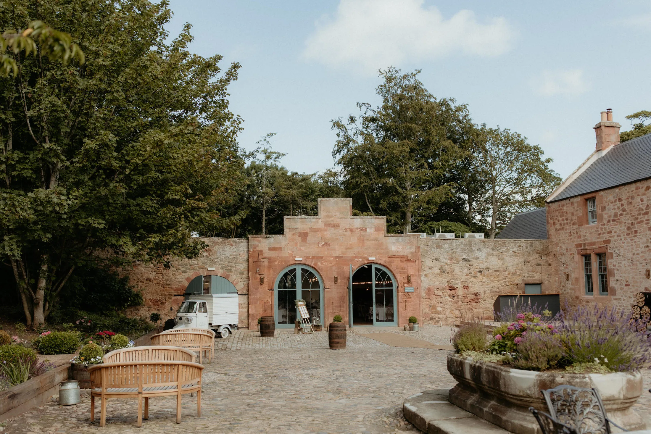 A wedding couple walking through Broxmouth Courtyard grounds.