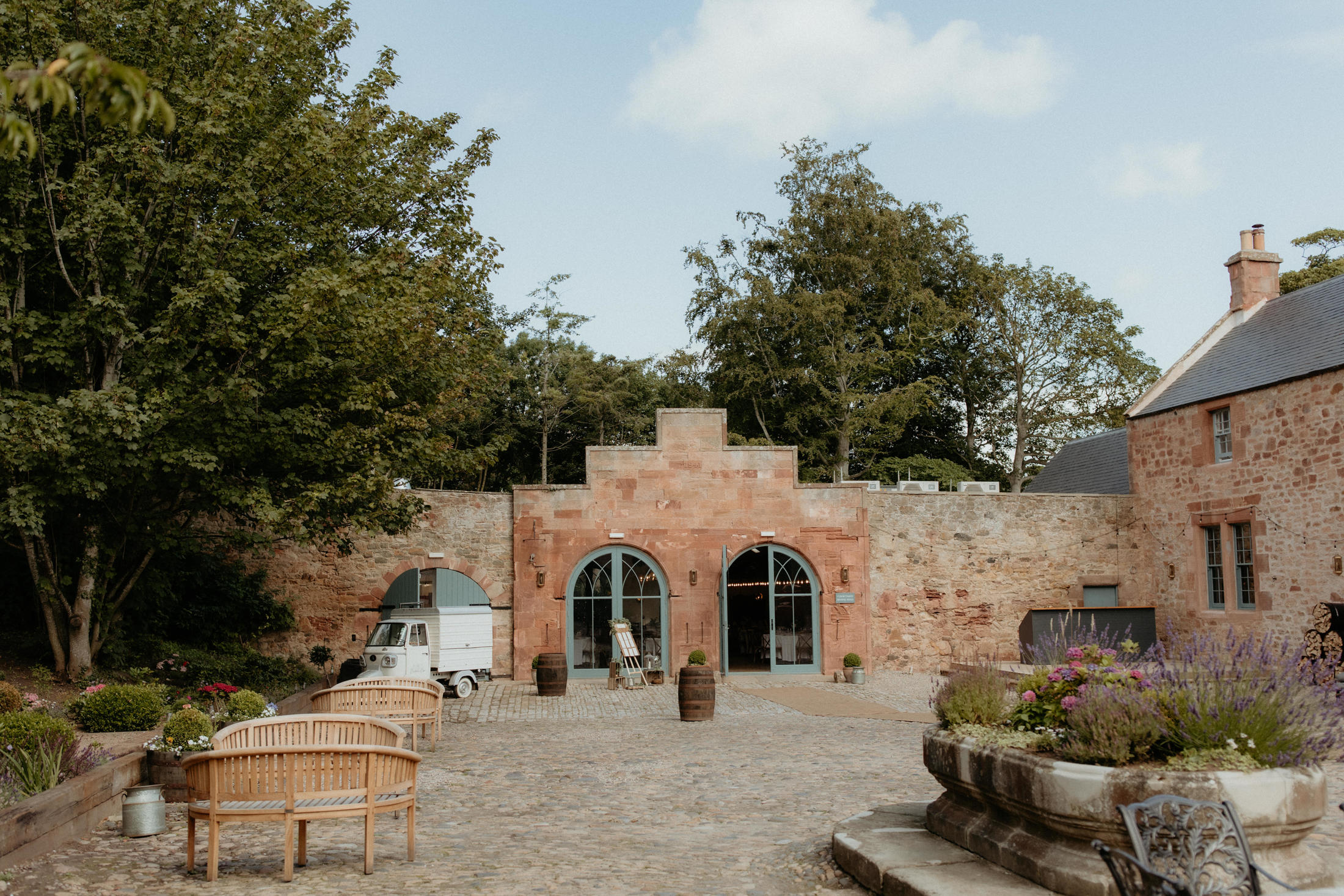 A wedding couple walking through Broxmouth Courtyard grounds.